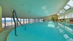 a large swimming pool with a view of the beach at Strand-Hotel Hübner in Warnemünde