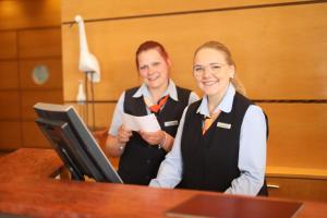 a man and a woman standing at a desk at Strand-Hotel Hübner in Warnemünde