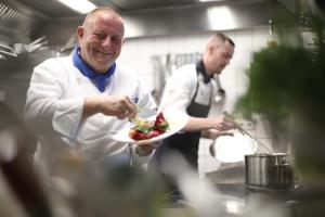 two chefs in a kitchen holding a plate of food at Strand-Hotel Hübner in Warnemünde