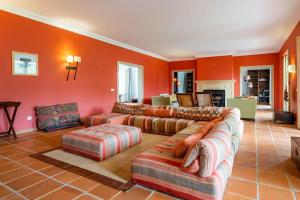 una sala de estar con paredes y sofás naranjas en Luxurious sprawling villa in Praia Del Rey, en Amoreira