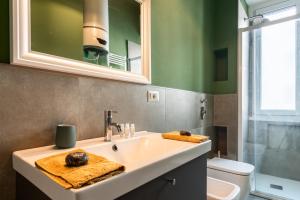 un bagno con lavandino, WC e specchio di Flora Flexyrent apartment AC a Milano Altre 19 foto