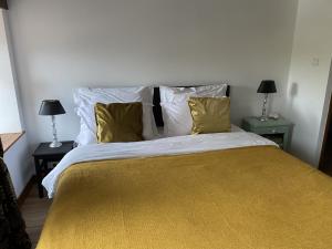 a bedroom with a large bed with yellow sheets and pillows at Les Pommiers d'Amfreville, Chambres d'hôtes & Table d'hôtes in Picauville