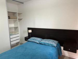 a bedroom with a blue bed with a black headboard at Apart Hotel Cañuelas in Cañuelas