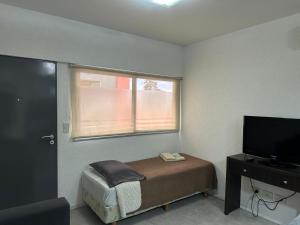 a small bedroom with a bed and a window at Apart Hotel Cañuelas in Cañuelas