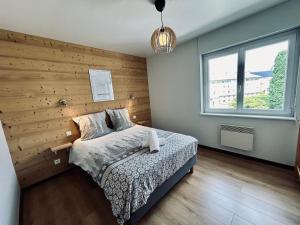 a bedroom with a wooden accent wall and a bed at La Perle de l'Eau - au bord du lac in Gérardmer