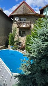 a swimming pool in front of a house with a christmas tree at Кам'яний двір in Mykulychyn