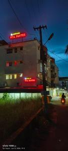 a train traveling past a building with a neon sign at VVP Service Apartments & Airport Suits in Cochin