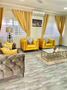 a living room with yellow couches and a table at Red Brick Apartments - In Central Accra - 15 Mins To Airport in Accra