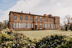 un vecchio edificio in mattoni con un ampio cortile di Chateau Beaudesert - Piscine - Tennis - Parc de 50Ha a Corbarieu