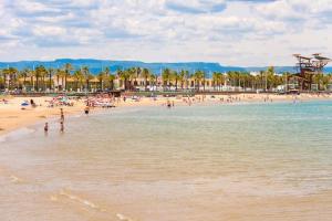 a beach with a bunch of people in the water at Palm Beach by Unik Vacation in La Pineda