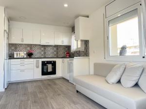 a living room with a white couch and a kitchen at Palm Beach by Unik Vacation in La Pineda