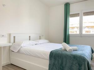 a white bedroom with a white bed and a window at Palm Beach by Unik Vacation in La Pineda