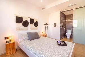 een witte slaapkamer met een bed en een badkamer bij Penthouse by Unik Vacation in Tarragona