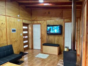 a living room with a couch and a tv on a wall at Ruta Archipiélago in Ancud
