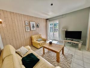 a living room with a couch and a tv at La Perle de l'Eau - au bord du lac in Gérardmer