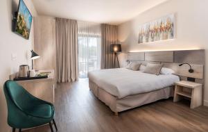 a hotel room with a bed and a green chair at Mas De La Senancole in Gordes