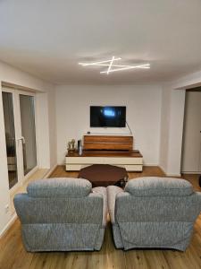 a living room with two couches and a flat screen tv at Messelodge Deiker Höfe in Düsseldorf