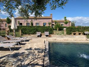 a pool with chairs and an umbrella next to a building at Resort Fonte Vulci in Canino