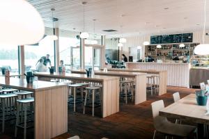 a restaurant with wooden tables and chairs and people at Ravintola Kiulu Oy in Ähtäri +7 photos