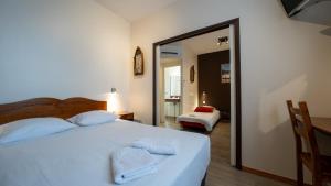 Un dormitorio con una cama blanca y un espejo. en Le Relais Du Canalou, en Digoin