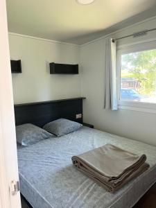 a bed in a bedroom with a window and a bedvisor at Mobil-home 3 chambres Premium - Camping la Faloise in Angicourt