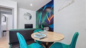 een eetkamer met een tafel en groene stoelen bij L'Oiseau du paradis, entre gare et centre ville, rez-de-chaussée, avec terrasse et parking privé in Moulins +24 foto's