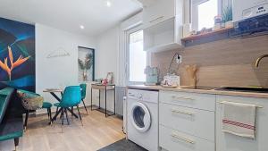 a kitchen with a washing machine and a table at Appartement Oiseau du Paradis avec terrasse parking privé proche centre in Moulins