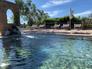 a swimming pool with chairs and a fountain at Resort Fonte Vulci in Canino