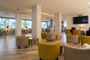 a lobby with yellow chairs and tables and chairs at Hotel Puerta de Toledo in Madrid