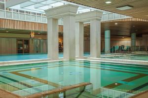 a swimming pool in a building with columns at Verdi Budapest Aquincum in Budapest