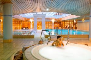 een jonge jongen zittend in een bad in een zwembad bij The Aquincum Hotel Budapest in Boedapest