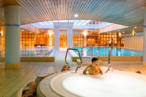 a young boy sitting in a bath tub in a swimming pool at Verdi Budapest Aquincum in Budapest