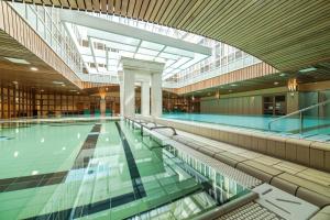 een zwembad in een gebouw met een bibliotheek bij The Aquincum Hotel Budapest in Boedapest