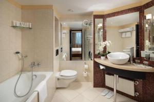 a bathroom with a tub and a toilet and a sink at Verdi Budapest Aquincum in Budapest