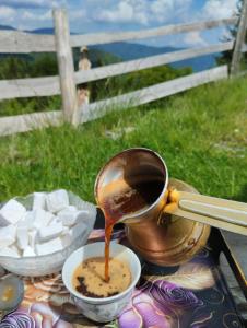 una teiera che versa caffè in una tazza sul tavolo di Cottage Vranica a Fojnica