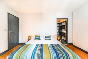 a bedroom with a bed with a colorful blanket at Appartement Climatisé 3 Chambres Vue Garonne in Bordeaux +10 photos