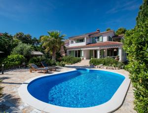 a swimming pool in front of a house at Holiday House Dolin in Rab