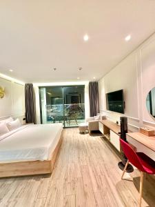 Schlafzimmer mit einem Bett, einem Schreibtisch und einem TV in der Unterkunft White House Condotel Phú Yên in Tuy Hoa
