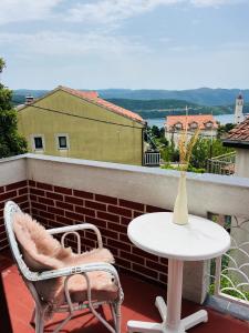 a table and chairs on a balcony with a vase at Holiday house in Neum