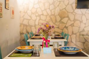 a table with plates and a vase of flowers on it at Greenlove in Agerola
