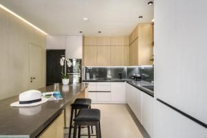 a kitchen with white cabinets and a counter with stools at New Beachfront Mesogaia Villa with Heated Pool, Jacuzzi & Playroom, 60m from the beach in Pigianos Kampos