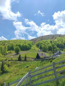 una staccionata di legno in un campo con una fattoria di Cottage Vranica a Fojnica