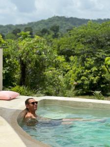 un uomo in una piscina con vista sugli alberi di La Mona Eco Cabins a Palomino