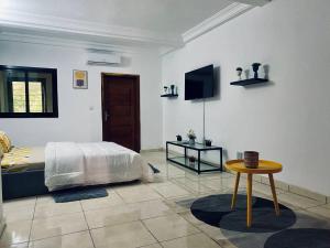 a bedroom with a bed and a table and a tv at Hotel Résidence Essiéniguet in Abidjan
