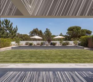 an external view of a lawn with umbrellas at Precious House in Comporta in Carvalhal