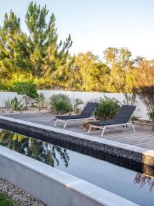 two lounge chairs sitting next to a swimming pool at Precious House in Comporta in Carvalhal