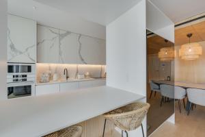 Una cocina con gabinetes blancos y una mesa y sillas. en Chic Two-Bedroom En Suite in Central Town - Savoy Residence, en Funchal