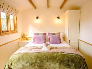 a bedroom with a bed with a teddy bear sitting on it at Lintmill Lodges - Thistle Shepherds Hut in Sorn