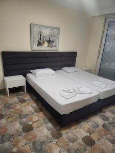 een slaapkamer met een groot bed met witte lakens bij Home holiday kozmai in Shëngjin