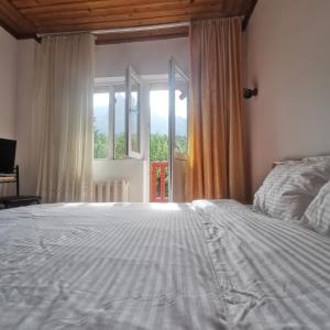 a bedroom with a large bed and a window at Pensiunea Fara Nume in Buşteni